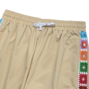 Detail of elastic waist with white drawstring and colorful floral stripes on beige pants