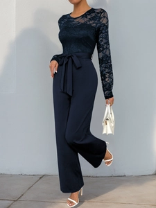 Close-up of elegant navy blue jumpsuit featuring intricate lace sleeves and belted waist detail