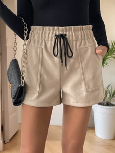 Detail of beige high-waisted shorts with elastic drawstring waist and large utility pockets