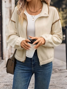 Detail of cream fleece jacket with brown trim and zipper closure in outdoor street style