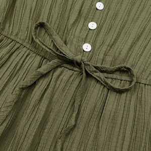 Detail of olive green pleated jumpsuit fabric with round buttons and waist tie