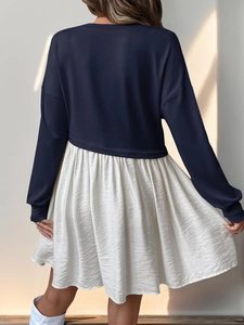 Détail d'une robe à manches longues bicolore avec haut sweat-shirt et jupe longue plissée