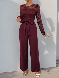 Close-up of burgundy jumpsuit with floral lace top and waist tie detail