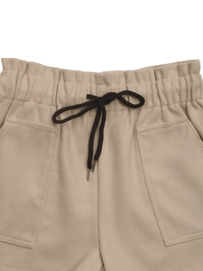 Detailed close-up of elastic waist with black drawstring on khaki wool fabric shorts