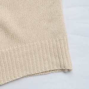 Detailed macro view of the ribbed hem and fine knit texture of the beige cardigan