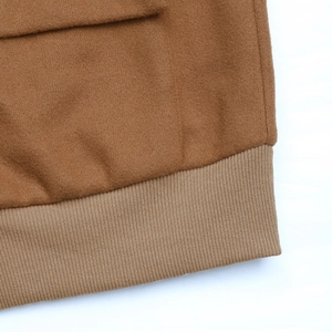 Detail of camel wool jacket showing ribbed hem stitching and flap pocket texture