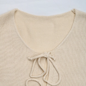 Close-up of cream knitted cardigan showing neck tie detail and soft knit texture