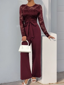 Detail of elegant burgundy lace jumpsuit with chic waist tie and wide-leg trousers