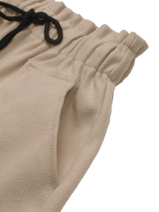Close-up of khaki wool shorts featuring an elastic waistband and black drawstrings
