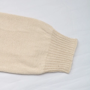 Macro detail of ribbed cuffs on a cream-colored knit cardigan showing weave texture