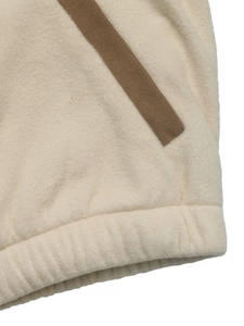 Detail of fleece jacket with brown corduroy pocket trim and elasticated hemline