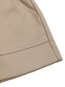 Close-up of side pocket stitching and hem details on light camel wool shorts