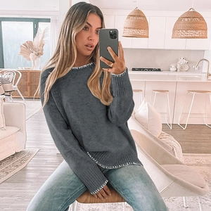 Detailed view of grey crewneck knit sweater featuring decorative white contrast stitching