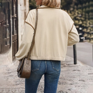 Women's cream fleece jacket with brown trim and elastic hem seen from back in street style