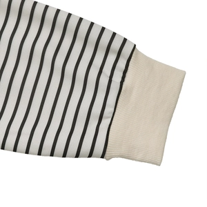 Détail de la manche à rayures noires et blanches avec poignet côtelé crème sur le sweat