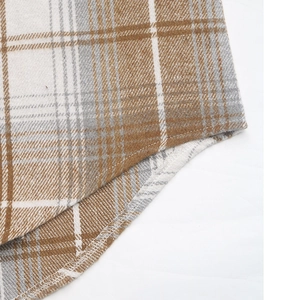 Macro detail of plaid shirt curved hem featuring brown and grey flannel fabric texture