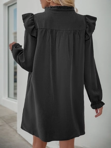 Detail view of the back of a dark gray long sleeve dress with ruffled trim and pleats