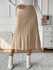 Close-up of the pleated knit texture and elastic high waist on a khaki midi skirt