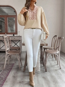 Detail of V-neckline featuring retro circular embroidery on apricot long sleeve blouse