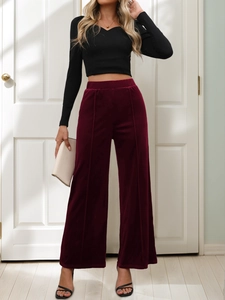 Detail of burgundy velvet wide-leg pants featuring vertical seams and high-waist design