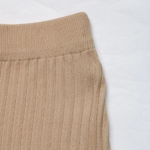 Detailed close-up of khaki pleated knit skirt with high elastic waistband and vertical texture