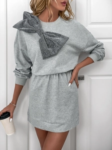 Detail of grey sweatshirt dress featuring a large silver sequin bow on the left shoulder