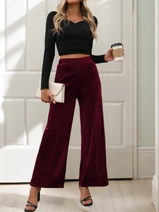 Macro shot of high-waist velvet wide-leg trousers in wine red with sharp center crease line