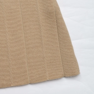 Detailed close-up of camel pleated knit fabric texture and vertical ribbed pattern hem