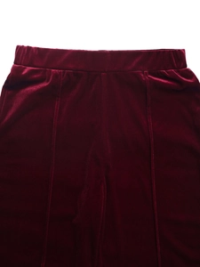 Detail of high-waist burgundy velvet wide-leg pants with elastic waistband and pleated lines
