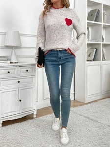 Close-up of a grey knit sweater with red heart embroidery and wavy edge details