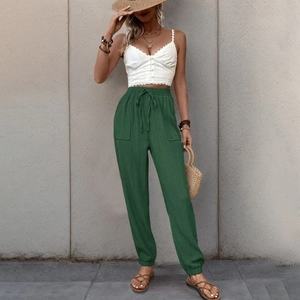 Dettaglio del crop top bianco con bottoni e pantaloni cargo verde oliva con lacci