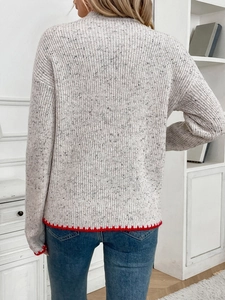 Women's light grey knit sweater with festive red scalloped trim and colorful specks