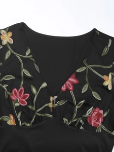 Detail of colorful floral embroidery on a black V-neck mesh bodysuit for women
