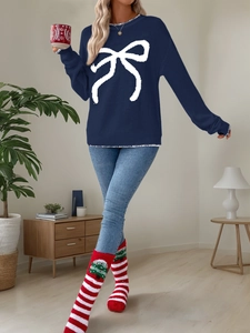 Detail of navy blue crewneck sweater with large white bow jacquard and festive accessories