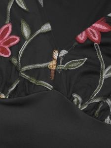 Close-up of deep V-neck with intricate floral embroidery on black mesh fabric