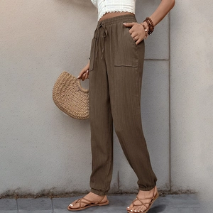 Dettaglio dei pantaloni marroni a vita alta con coulisse elastica e grandi tasche