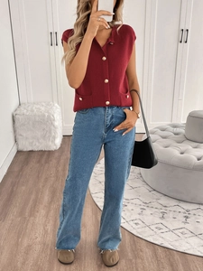 Detail of burgundy knit cardigan vest with gold buttons paired with blue straight jeans