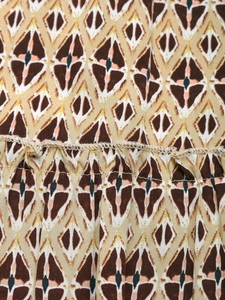 Detailed close-up of geometric diamond print fabric with smocked waist seam and fine stitching
