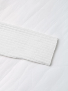 Detailed macro shot of white ribbed knit cuff showcasing texture and quality fabric