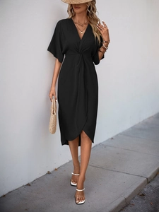 Detail of elegant black V-neck dress featuring twist waist and cross-split hem