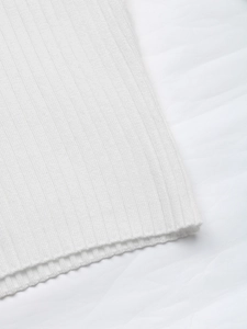 Detailed macro view of white ribbed knit fabric texture on the stylish off-shoulder sweater