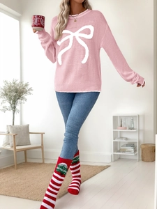 Detail of soft pink knit sweater featuring a large white jacquard bow and ribbed crewneck