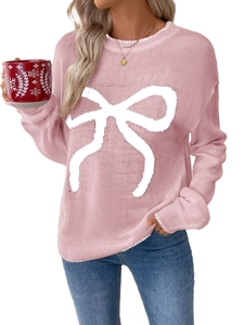 Close-up of pink knit sweater with white bow pattern and ribbed cuff details