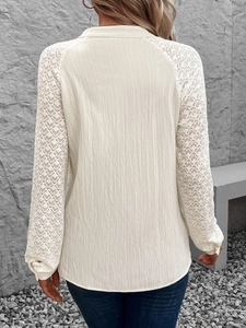 Detail eines cremeweißen Langarmshirts mit Strukturstoff und Spitzenbesatz am Ärmel