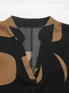 Close-up of a women's V-neck shirt with brown leaf print on lightweight black fabric