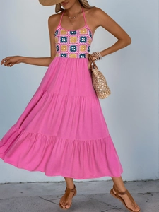 Detail of bohemian halter dress featuring a colorful crochet bodice and pink tiered skirt