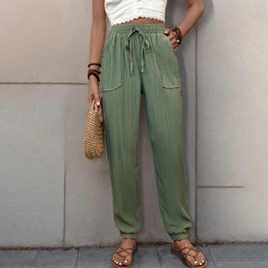 Dettaglio dei pantaloni joggers verde erba a vita alta con coulisse e texture