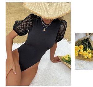 Detail of black rib-knit bodysuit with mesh puff sleeves on a sunny beach setting