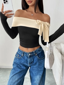 Detail of off-shoulder long sleeve top with large bow accent and contrast trim