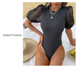 Detail of elegant black bodysuit with puff mesh sleeves and ribbed texture on beach background